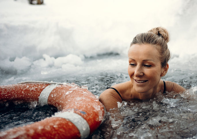 Frau im beim Eisbaden im Winter in zugefrorenen Teich mit Rettungsring im Bleib Berg