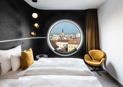 Innenanischt des Zimmers im Mooons Hotel Vienna mit Aussicht auf die Stadt durch rundes Panoramafenster