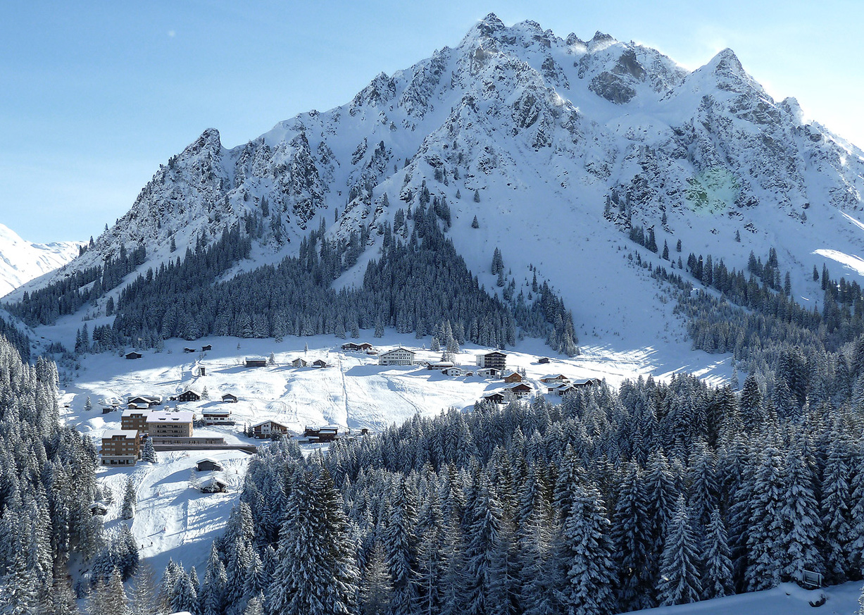 Blick von oben auf Berg mit Schnee und dem Bergdorf Gargellen in Vorarlberg